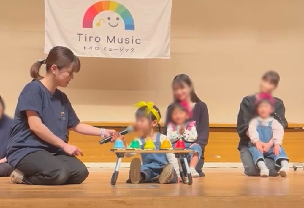 ステージで一人で前に出てデスクベルを鳴らす女の子の様子