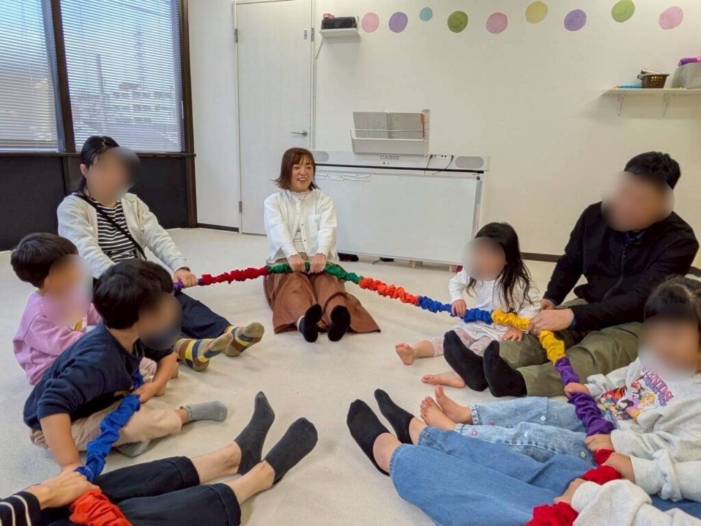 リトミックレッスンでドリームバンドを使う子どもたちの様子