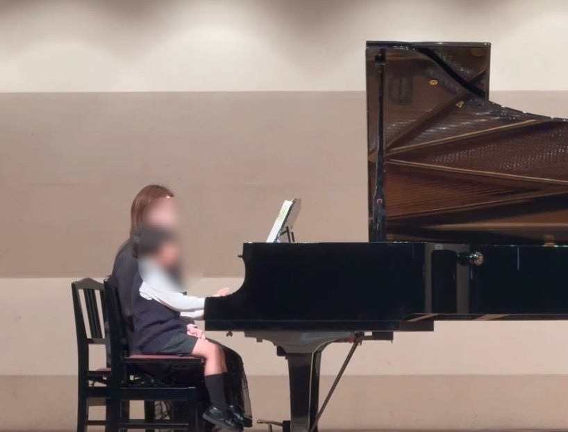 ピアノの発表会で講師との連弾をする男の子の写真